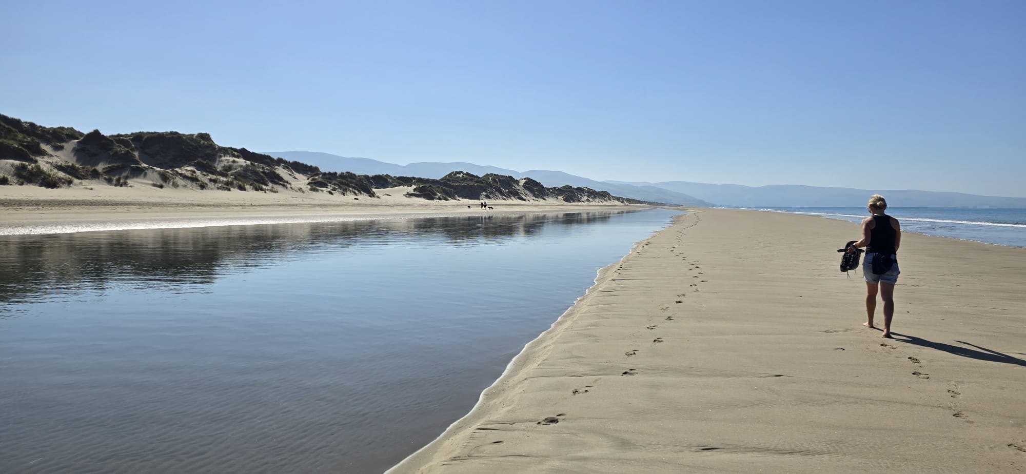 A lone walker on the sand with mountains beyond