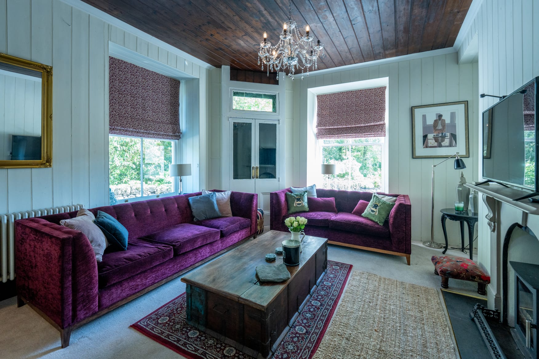 The lounge with velvet sofas, woodburner and crystal chandelier