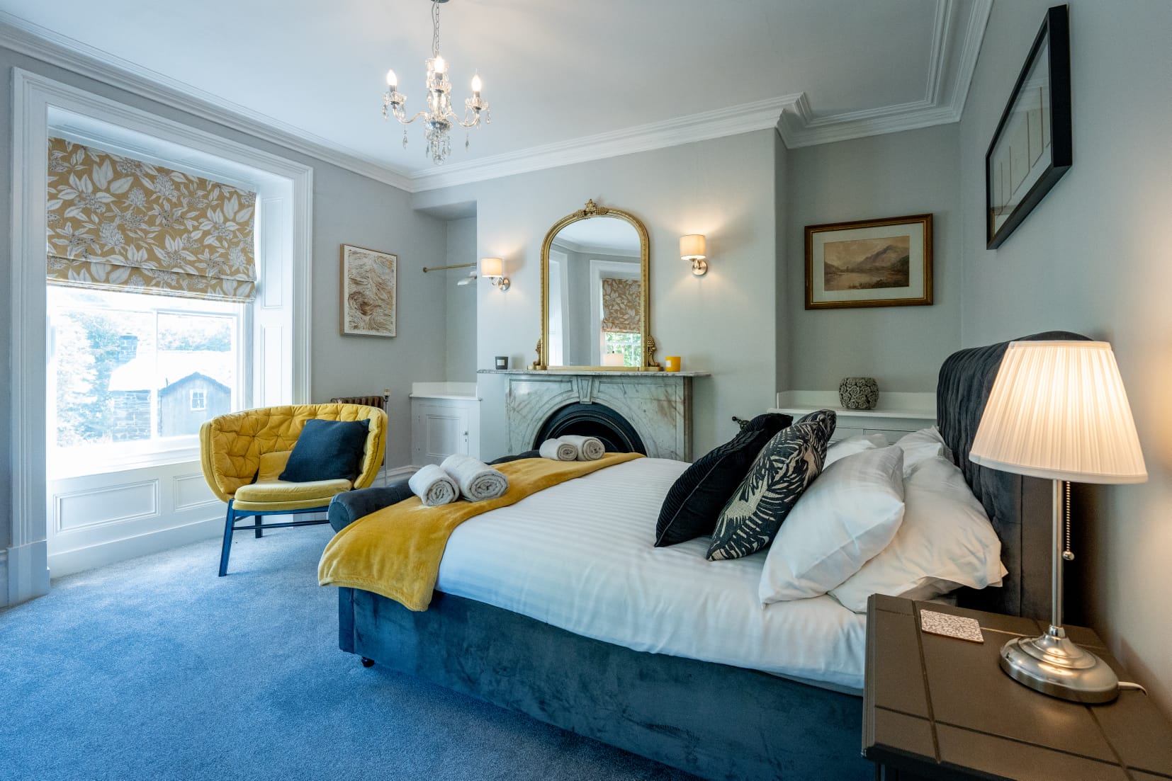 Master double bedroom with grey velvet bed, marble fireplace and gold mirror
